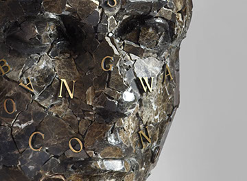 La scultura Silence un viso frammentato che rappresenta la terra distrutta con lettere in bronzo che cercano di risanare le crepe. D'Angelo