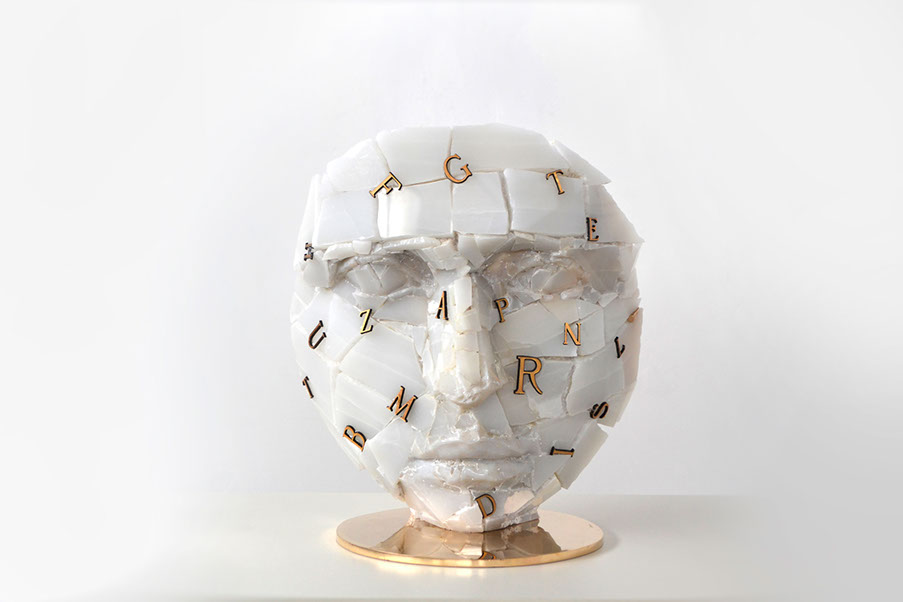 Giuseppe D'Angelo scultura un viso in onice bianco distrutto con delle lettere che creano un rebus. Opera , arte